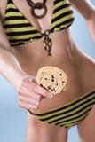 Woman chest down wearning a swimsuit and holding a cookie away from her body