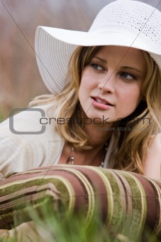 Woman In Hat Lying in Grass With Pillow