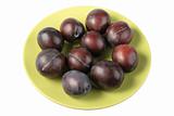 Group of dark-purple plums on plate.