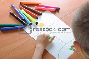 boy drawing on paper with crayons 