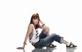 Confused young female dancer sitting on shiny floor on white background