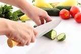   Someone cutting a cucumber, and slice flying isolated on white