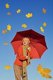 Happy woman with umbrella and falling yellow leaves