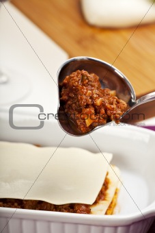 making a lasagna by pouring the sauce