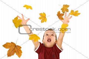 Happy boy reaching for the falling autumn leaves