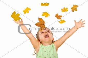 Happy shouting little girl with falling autumn leaves