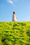 Little girl on a green grass hill