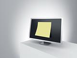 Monitor on a podium with oversized post it note.