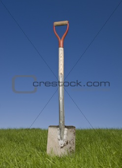 Shovel in green grass against a blue sky