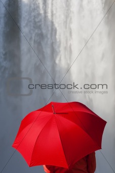 Woman With a Red Umbrella In Front Of A Waterfall