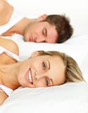 Couple lying in bed and woman smiling at the camera