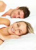 Couple resting in bed and woman smiling at the camera