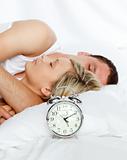 Couple in bed with focus in alarm clock