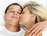 Girlfriend kissing her boyfriend in bed