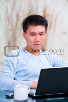 Young Chinese man using laptop