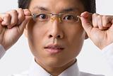 Asian businessman holding glasses to camera
