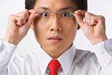 Asian businessman surprised holding glasses to camera