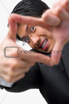 Asian businessman looking at his perspetive by framing his finge
