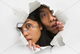 Two people peeking from hole in wall