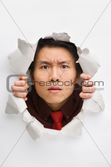 Man gazing seriously from hole in wall
