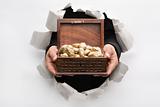 Hand breakthrough wall holding treasure chest full of golden nug