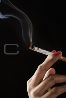 female fingers holding burning cigarette