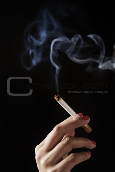 female fingers holding burning cigarette