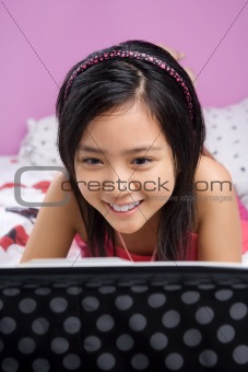 Young girl using laptop in her bedroom