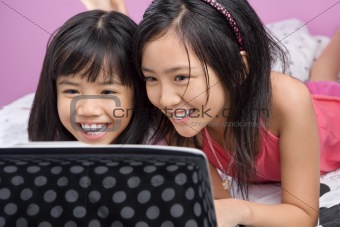 Two little girls playing with laptop