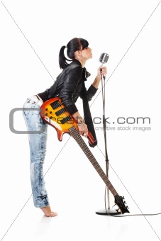 Rock-n-roll girl holding a guitar singing into retro microphone isolated on white