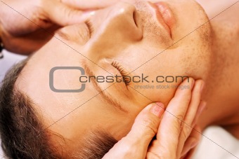  man lying, gets massage, reiki,acupressure on his face