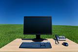 Desk and Computer In Green Field 