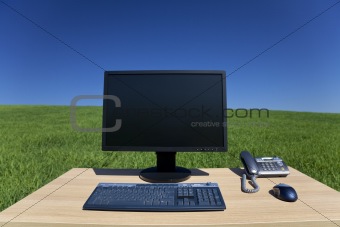 Desk and Computer In Green Field 