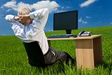 Businessman Relaxing at Desk With Computer In A Green Field