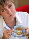 Young woman in blue necklace drinking tea