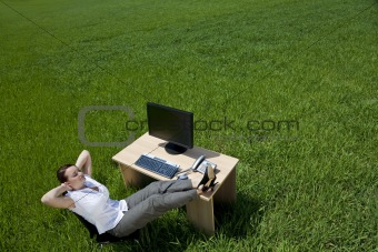 Woman Relaxing At An Office Desk In A Green Field