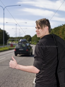 A young man hitchiking on the road