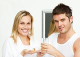 Woman holding pills and man drinking orange juice
