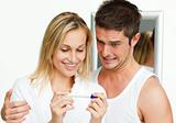 Happy couple examining a pregnancy test smiling at the camera