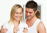 Happy couple examining a pregnancy test smiling at the camera