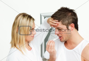 Worried woman examining a man with a termomether