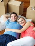 Happy couple on floor after moving with thumbs up