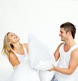 Young couple having a pillow fight with copy-space