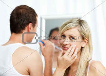 Woman putting cream on her face and man cleaning teeth