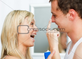 Woman having fun and putting cream on her boyfriend's nose