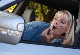 Attractive Woman Putting on Lipstick While Driving.