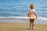 Blond little girl with sandy legs on the beach