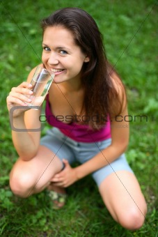 A girl drinks water from glass.