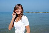 Beautiful woman by the sea with a mobile phone