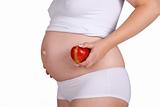 Presenting healthy apple in front of pregnant belly